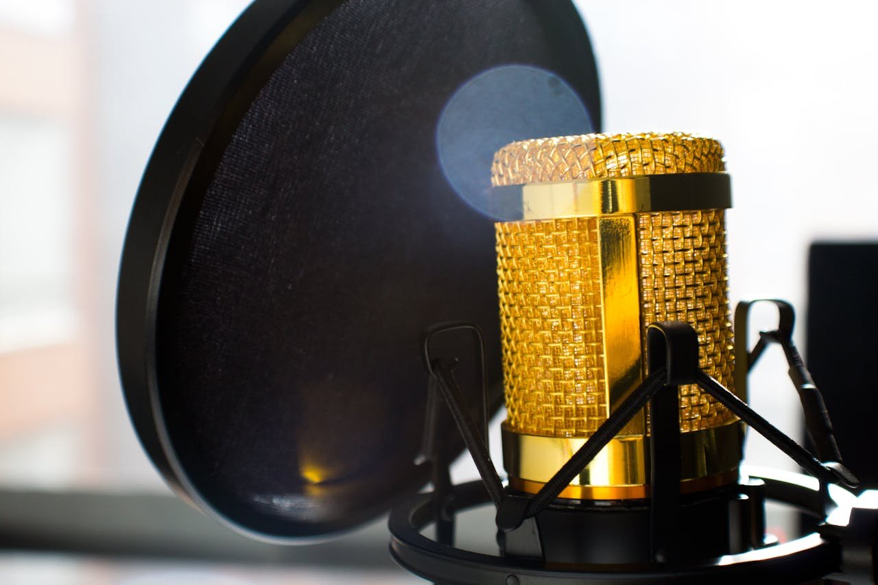 Close-up of a gold studio microphone with pop filter, ideal for recording and broadcasting.